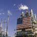 Part of oil refinery complex with big american flag displayed. Fumes coming out from the chimney.
