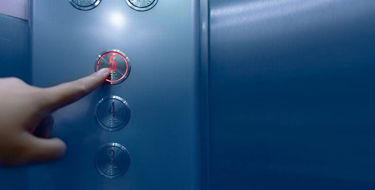 Person pressing on the fifth floor of elevator button. Hand press number 5 on button inside office or hotel lift. Index finger press on lift button. Claustrophobia. People stuck in lift. Braille code.