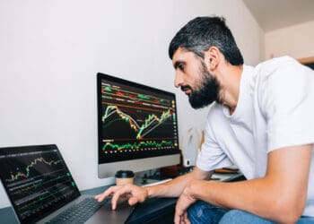 Caucasian businessman trading online, using computer technology, looking on stock exchange trade and analyzing