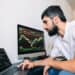 Caucasian businessman trading online, using computer technology, looking on stock exchange trade and analyzing