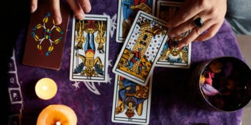 Close-up of a fortune teller reading tarot cards on a table with purple tablecloth