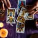 Close-up of a fortune teller reading tarot cards on a table with purple tablecloth