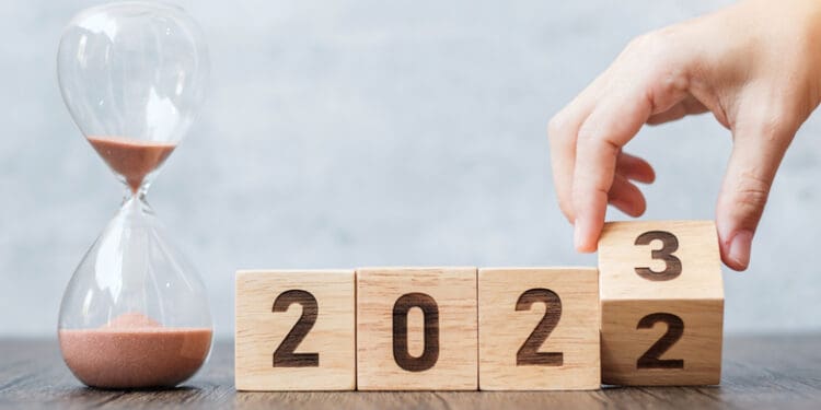 hand flip block 2022 to 2023 text with hourglass on table. Resolution, time, plan, goal, motivation, reboot, countdown and New Year holiday concepts