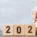 hand flip block 2022 to 2023 text with hourglass on table. Resolution, time, plan, goal, motivation, reboot, countdown and New Year holiday concepts