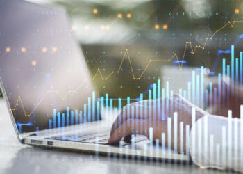 Close up of businessman hands using laptop with abstract glowing and growing business graph hologram on blurry outdoor background. Planning and strategy, stock market, business growth, progress and financial success concept. Double exposure.