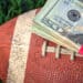 close up of wrapped money stack on football and green grass background